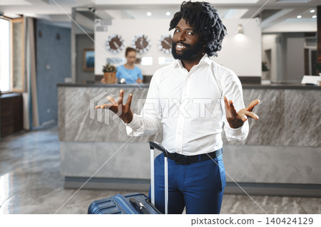 Black businessman with packed luggage standing in hotel lobby Black businessman with packed luggage standing in hotel lobby 140424129