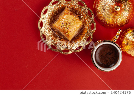 Turkish baklava and coffee in oriental dishware on red background Turkish baklava and coffee in oriental dishware on red background 140424176