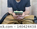 Man sitting on the toilet with a smartphone in hands. Guy scrolling phone on the loo, concept of prolonged sitting risk, screen addiction, and hemorrhoids. Man sitting on the toilet with a smartphone in hands. Guy scrolling phone on the loo, concept of prolonged sitting risk, screen addiction, and hemorrhoids. 140424438