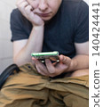 Man sitting on the toilet with a smartphone in hands. Guy scrolling phone on the loo, concept of prolonged sitting risk, screen addiction, and hemorrhoids. Man sitting on the toilet with a smartphone in hands. Guy scrolling phone on the loo, concept of prolonged sitting risk, screen addiction, and hemorrhoids. 140424441