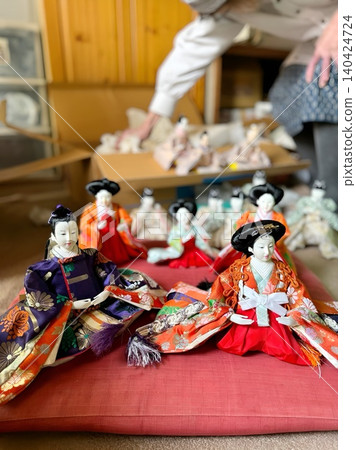An elderly woman's hands as she puts Hina dolls into a cardboard box (vertical view) An elderly woman's hands as she puts Hina dolls into a cardboard box (vertical view) 140424724
