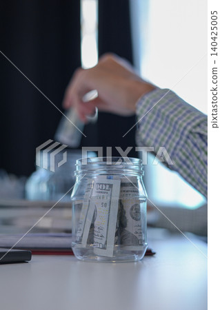 Business Man Putting US Dollar Bill into Saving Jar for Financial Planning and Saving Concept Business Man Putting US Dollar Bill into Saving Jar for Financial Planning and Saving Concept 140425005