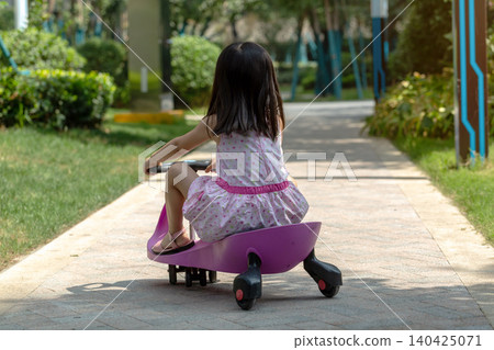 Cute Asian Little Girl Riding Wiggle Car Outdoors in Sunny Park Cute Asian Little Girl Riding Wiggle Car Outdoors in Sunny Park 140425071