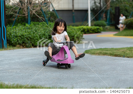 Cute Asian Little Girl Riding Wiggle Car Outdoors in Sunny Park Cute Asian Little Girl Riding Wiggle Car Outdoors in Sunny Park 140425073