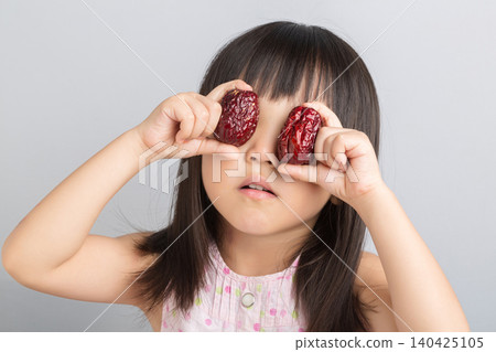 Cute Asian Little Girl Holding Red Date Fruit and Smiling Cute Asian Little Girl Holding Red Date Fruit and Smiling 140425105