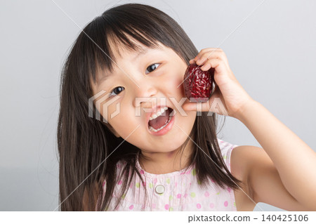 Cute Asian Little Girl Holding Red Date Fruit and Smiling Cute Asian Little Girl Holding Red Date Fruit and Smiling 140425106
