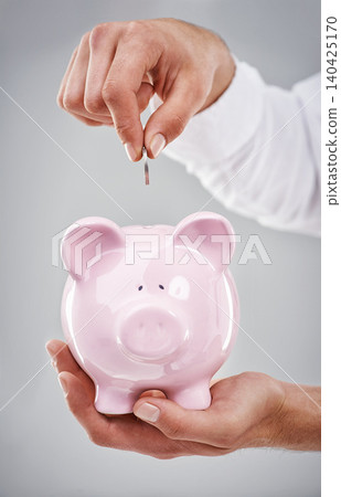 Hands, coin in piggy bank and saving for future, person has financial freedom or budget with money on grey background. Investment, finance for growth and development with security and emergency fund Hands, coin in piggy bank and saving for future, person has financial freedom or budget with money on grey background. Investment, finance for growth and development with security and emergency fund 140425170