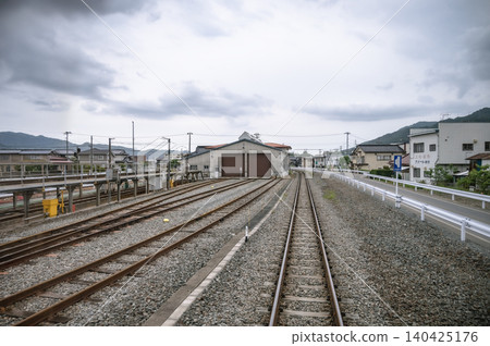 A landscape of a local railway's train depot and multiple parallel tracks spread out under a cloudy sky. A landscape of a local railway's train depot and multiple parallel tracks spread out under a cloudy sky. 140425176
