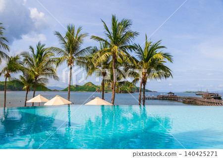 Luxury tropical resort swimming pool with palm trees and ocean view 140425271