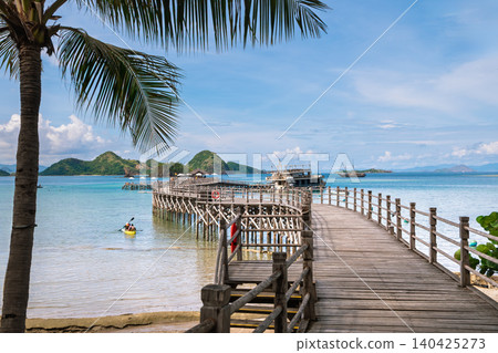 Wooden pier leading to tropical beach with ocean and islands 140425273
