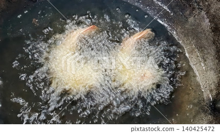 Deep-frying breaded shrimp in hot boiling oil in a wok pan Deep-frying breaded shrimp in hot boiling oil in a wok pan 140425472