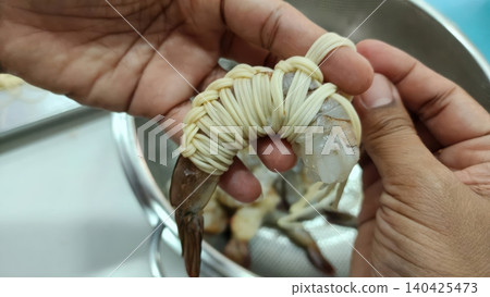 Chef hand wrapping raw shrimp with noodles for cooking appetizer Chef hand wrapping raw shrimp with noodles for cooking appetizer 140425473
