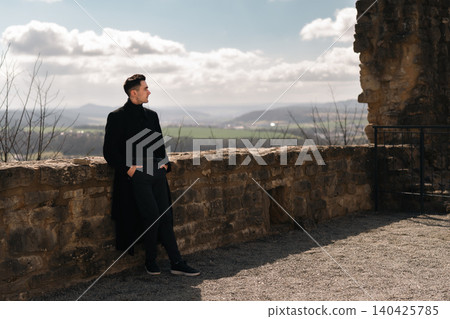Elegant Male Traveler Leaning on Castle Ruins Elegant Male Traveler Leaning on Castle Ruins 140425785