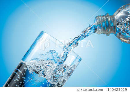 Clear drinking carbonated water pouring into a tall glass from a transparent plastic bottle. Clear drinking carbonated water pouring into a tall glass from a transparent plastic bottle. 140425929