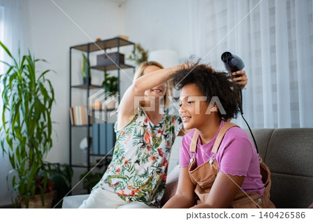Mother drying her mixed-race daughter's curly hair at home Mother drying her mixed-race daughter's curly hair at home 140426586