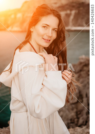Woman sunset sea young woman in white hoodie enjoys peaceful moment by the coast during golden hour Woman sunset sea young woman in white hoodie enjoys peaceful moment by the coast during golden hour 140426683