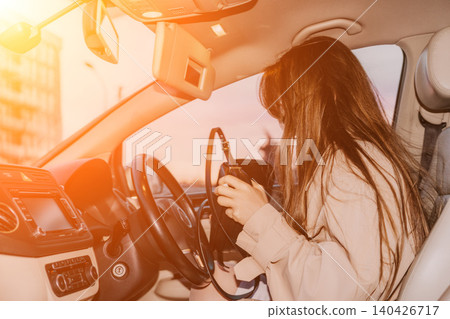 Car interior woman searching through her handbag while sitting in the driver seat at sunset Car interior woman searching through her handbag while sitting in the driver seat at sunset 140426717