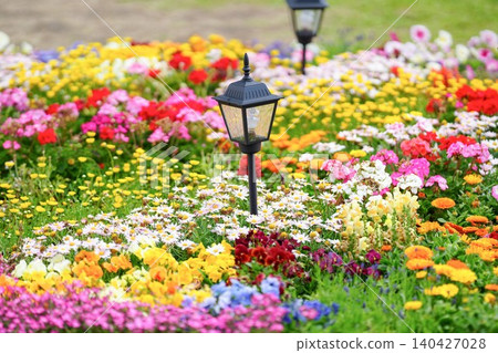 A flowerbed overflowing with brightly colored flowers and antique-style garden lights. A flowerbed overflowing with brightly colored flowers and antique-style garden lights. 140427028