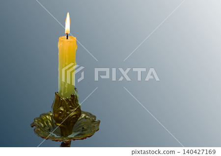 Burning candle in bronze candlestick on silver blue gray 140427169