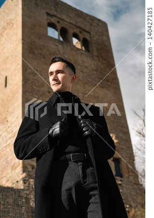 Stylish Man in Black Coat Near Historic Tower Stylish Man in Black Coat Near Historic Tower 140427185