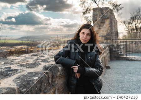 Young Woman in Black Jacket Leaning on Stone Wall Young Woman in Black Jacket Leaning on Stone Wall 140427210