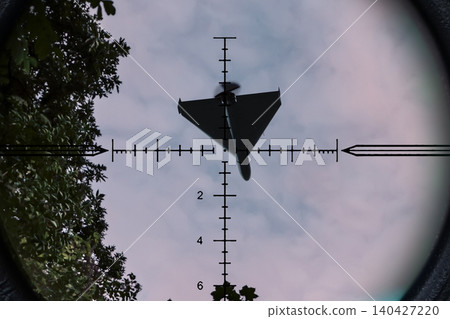 Strike drone appears in optical scope crosshair against sky and trees background. Strike drone appears in optical scope crosshair against sky and trees background. 140427220
