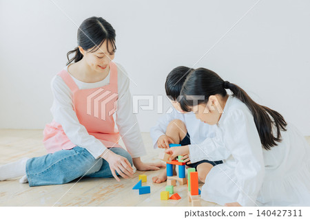 Children playing with building blocks with a childcare worker Children playing with building blocks with a childcare worker 140427311