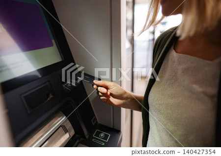 Woman inserting credit card into ATM for banking transaction Woman inserting credit card into ATM for banking transaction 140427354