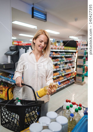 Woman buying cooking oil in grocery store 140427395