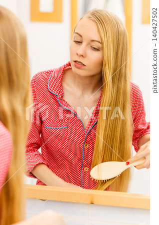 Woman brushing her long hair in bathroom Woman brushing her long hair in bathroom 140427502