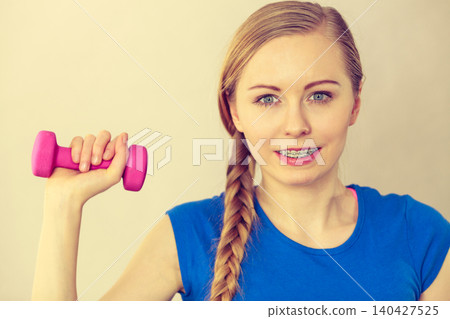Teenage woman working out at home with dumbbell Teenage woman working out at home with dumbbell 140427525