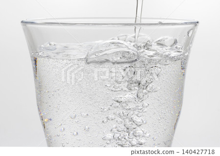 將碳酸水倒入玻璃杯中 將碳酸水倒入玻璃杯中 140427718