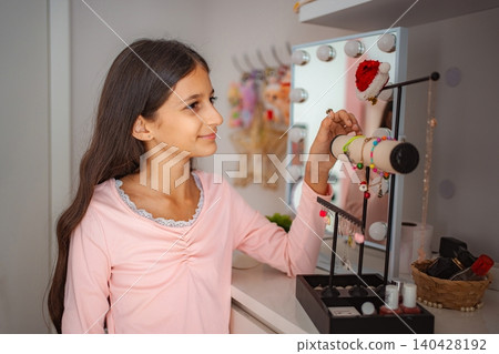 Young girl choosing bracelet from vanity jewelry stand 140428192