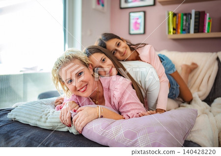 Mother and daughters relaxing together on couch at home 140428220