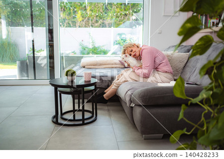 Mid adult woman relaxing on couch cuddling dog 140428233