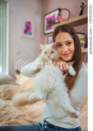 Teenager girl hugging fluffy white cat indoors Teenager girl hugging fluffy white cat indoors 140428261