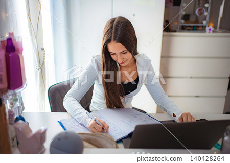 Teenage girl studying, writing notes, using laptop for online learning Teenage girl studying, writing notes, using laptop for online learning 140428264