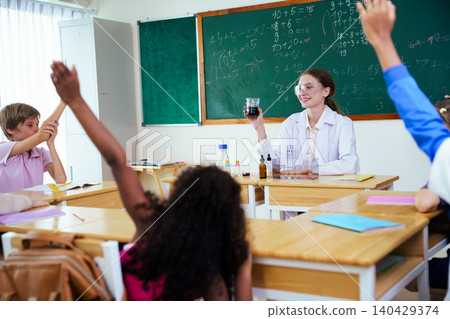 Diverse students raising hands to answer teacher in classroom Diverse students raising hands to answer teacher in classroom 140429374
