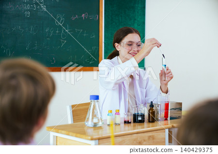 Female teacher doing a science experiment for elementary students Female teacher doing a science experiment for elementary students 140429375