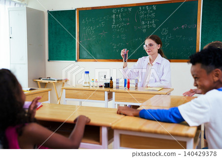 Female teacher doing a science experiment for elementary students Female teacher doing a science experiment for elementary students 140429378