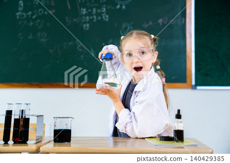 Caucasian schoolgirl holding erlenmeyer flask and smiling in science class 140429385