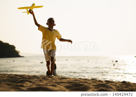 Happy Black boy running with toy airplane on the beach Happy Black boy running with toy airplane on the beach 140429472