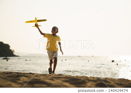 Happy Black boy running with toy airplane on the beach Happy Black boy running with toy airplane on the beach 140429474