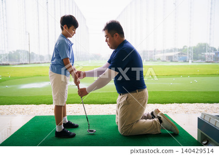 Professional golf coach teaching basic grip to young boy Professional golf coach teaching basic grip to young boy 140429514