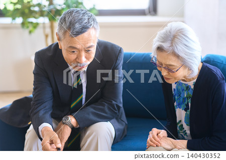 一位老年男子和一位老年女子坐在沙發上討論文件。 140430352