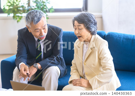 諮詢現場場景：一對老年夫婦在文件前聆聽解釋。 140430363