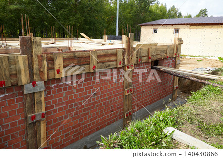 Brick foundation wall with wooden formwork and supports for concrete pouring. Brick foundation wall with wooden formwork and supports for concrete pouring. 140430866
