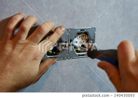 Close-up of electrician fixing wall sockets with screwdriver. Close-up of electrician fixing wall sockets with screwdriver. 140430893