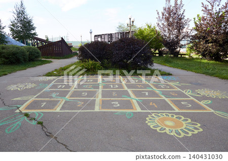 Children are seen enjoying a game of hopscotch on a painted sidewalk with numbers and flowers. Children are seen enjoying a game of hopscotch on a painted sidewalk with numbers and flowers. 140431030