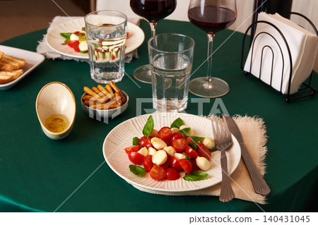 Plates of Caprese salad with tomatoes, cheese, and bread are set on the table Plates of Caprese salad with tomatoes, cheese, and bread are set on the table 140431045